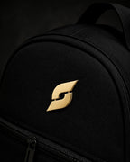 Trainimals goldener "Pflatsch"-Pin auf schwarzem Rucksack, 30mm Durchmesser, mit Sicherheitsverschluss.