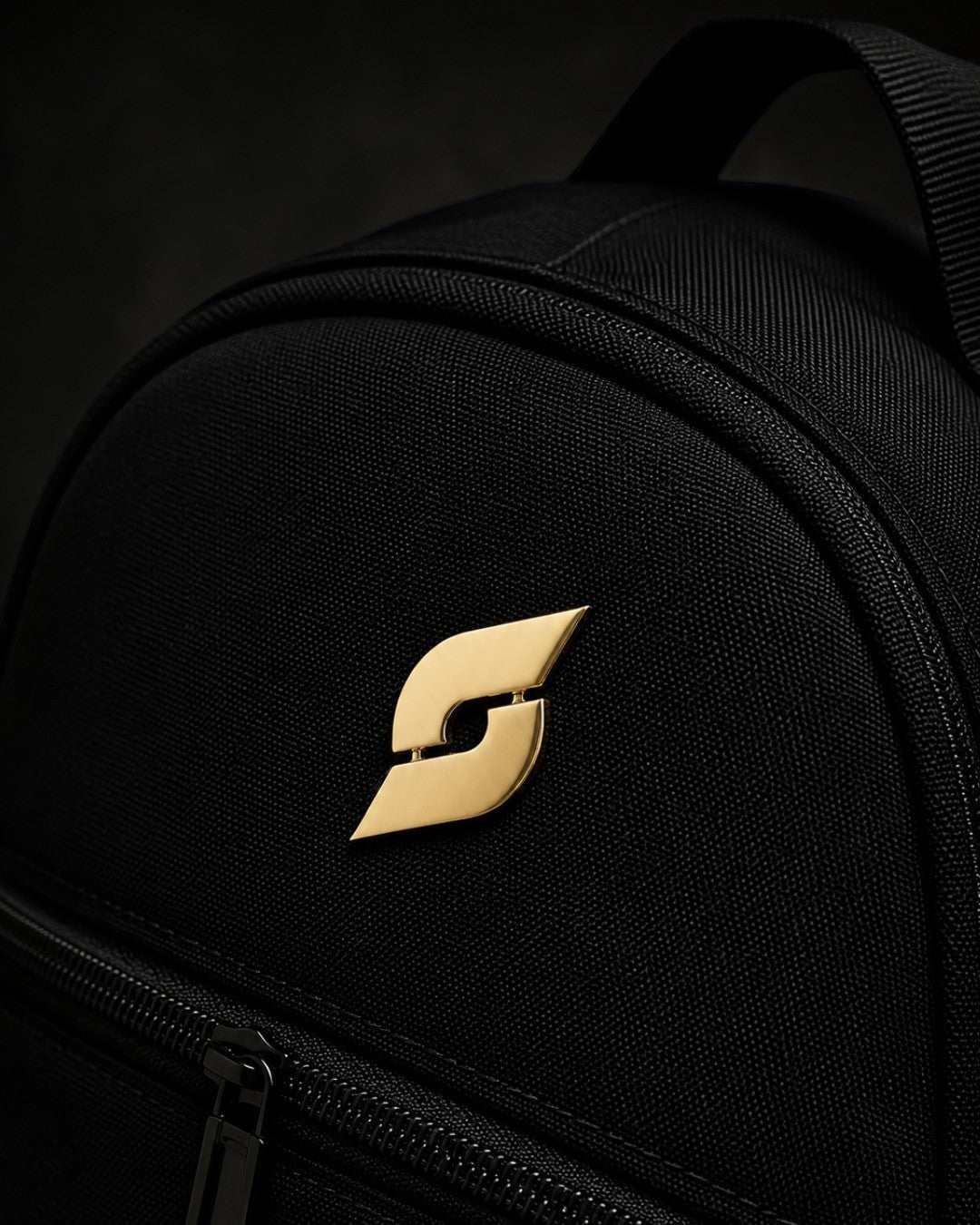 Trainimals goldener "Pflatsch"-Pin auf schwarzem Rucksack, 30mm Durchmesser, mit Sicherheitsverschluss.